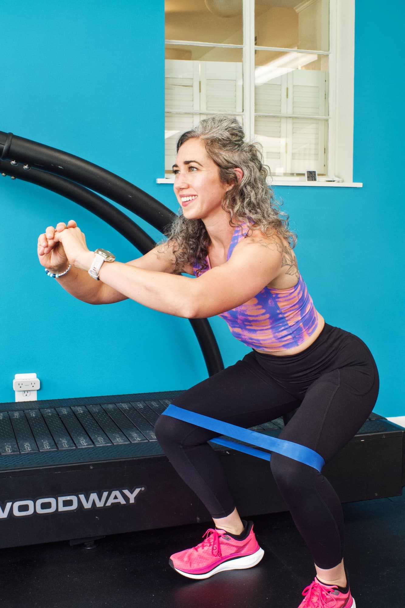 Tarah Romano doing banded squats on the studio treadmill
